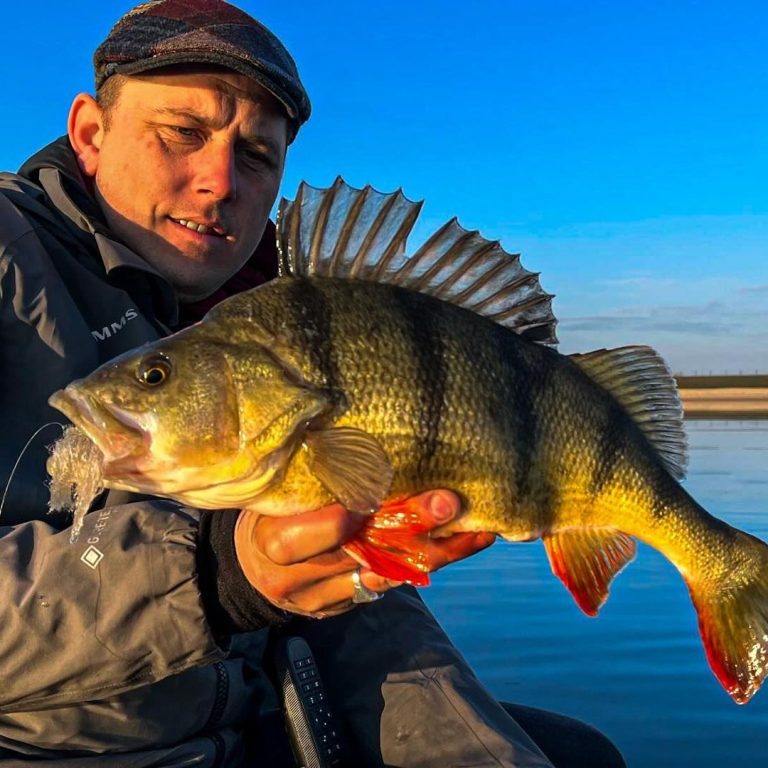 Blonde jongen in een boot toont een grote snoekbaars die hij heeft gevangen.