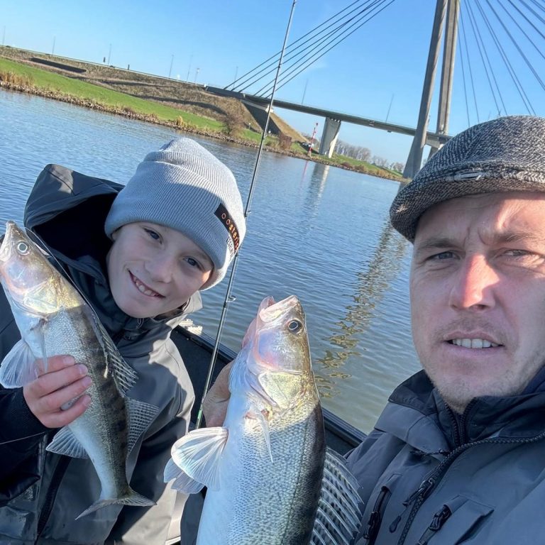 Blonde jongen in een boot toont een grote snoekbaars die hij heeft gevangen.
