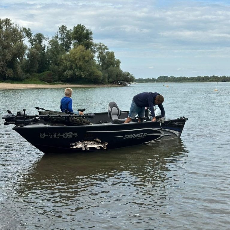 Twee mensen op een vissersboot in een rivier, bezig met hun visuitrusting.